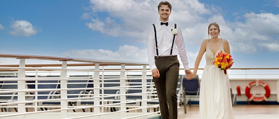 a married couple holds hands while walking on the deck