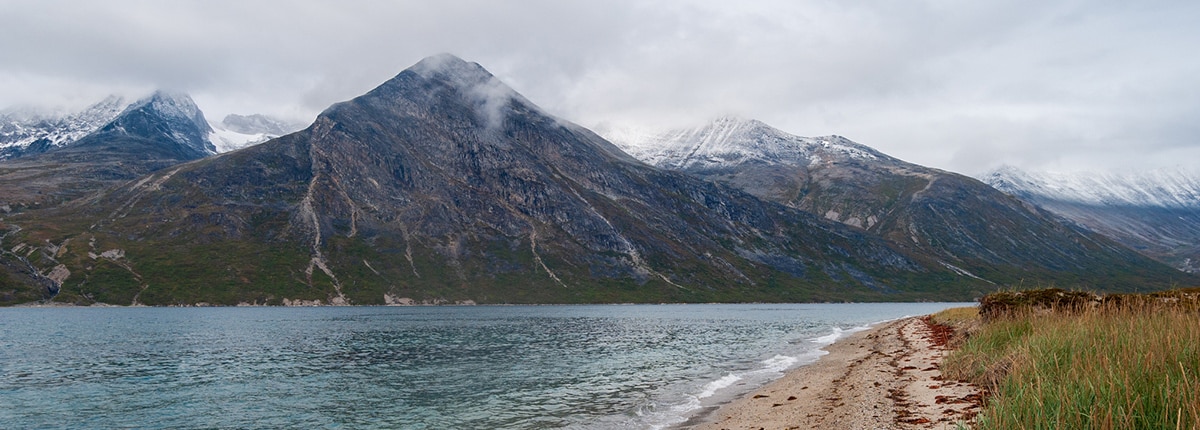 houses along a lake with the mountains in the background in nanortalik