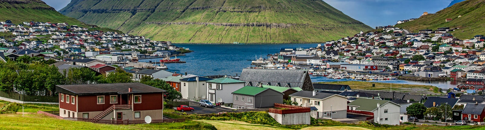 panoramic view of beautiful houses with mountain in runavik, faroe islands