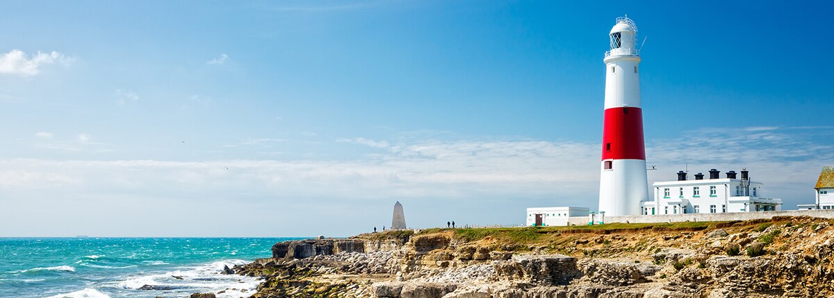 a red and white lighthouse is located on the edge of a cliff