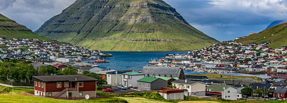 panoramic view of beautiful houses with mountain in runavik, faroe islands