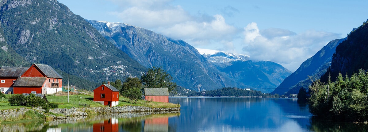 red fishing houses along the water with mountains in the background