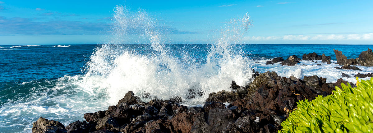 waves crashing into the rock lined coastline in kona