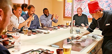 guests cheer as they watch a chef prepare a meal at bonsai teppanyaki