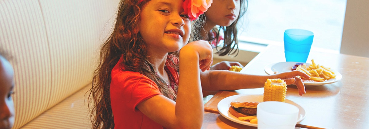 little girl smiles while enjoying her camp kids lunch 