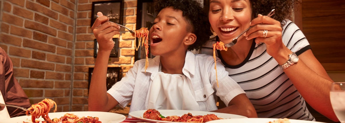 a boy eating delicious pasta 