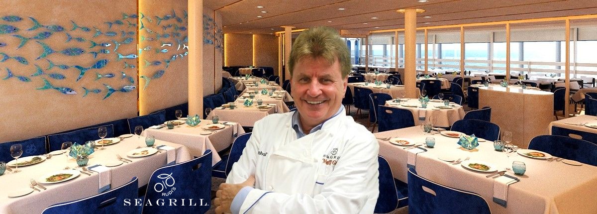 rudi holding a colorful plate of food with a view of the restaurant behind him