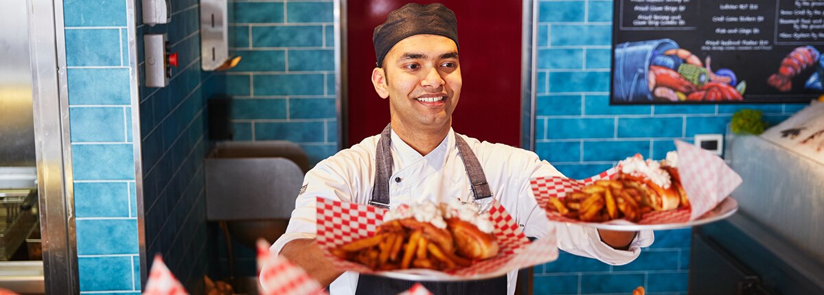 a staff serves two plates of seafood at seafood shack