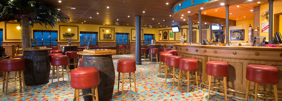 red bar stools around a wood bar and barrel-shaped tables in the colorful redfrog pub