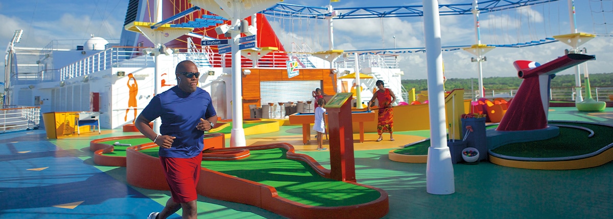 man running on the jogging track while people play in the back