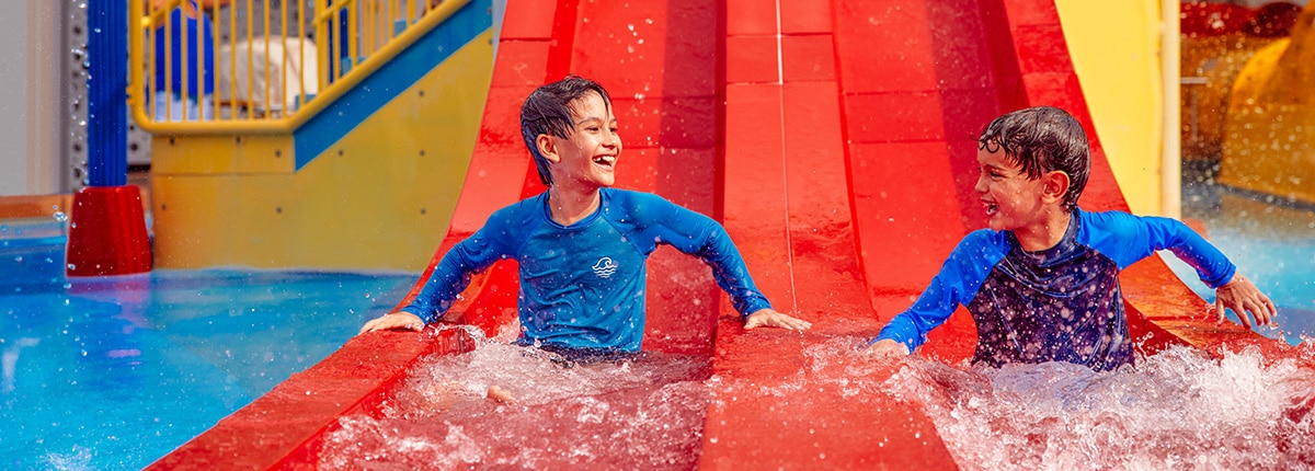 kids going down the slide and having fun in the carnival waterworks area onboard the ship