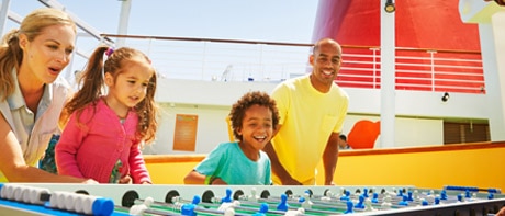 a man, a woman and two children playing foosball